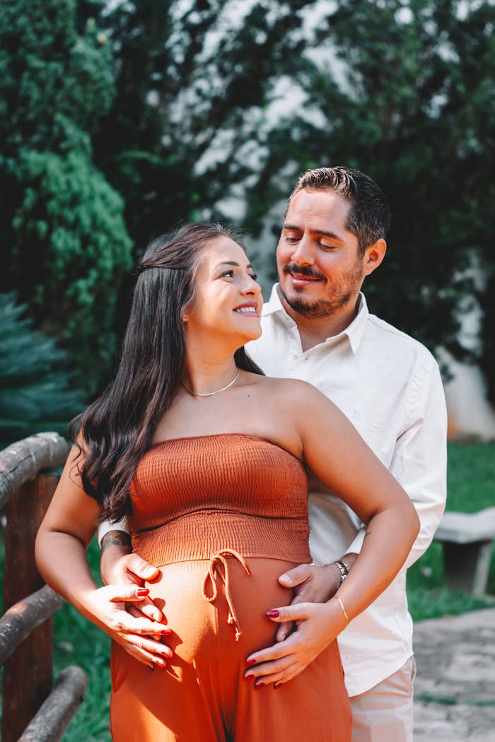 A joyful couple embracing in a lush outdoor setting, highlighting pregnancy happiness.