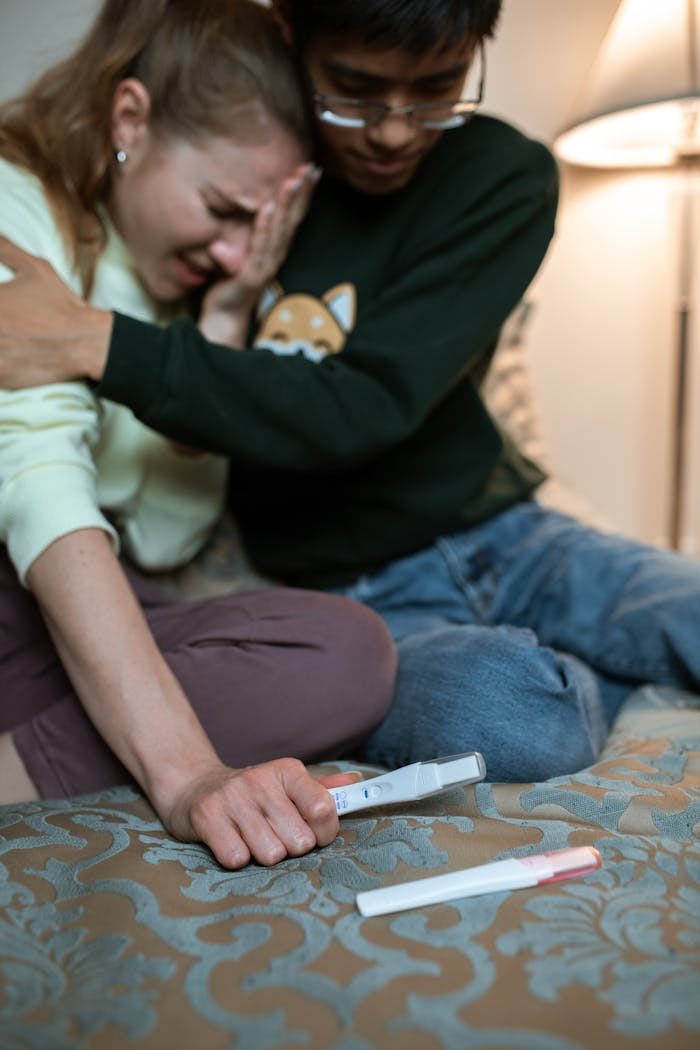 Couple embracing with emotional reaction to positive pregnancy test results.